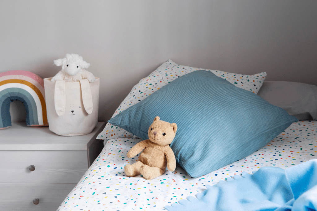 cama de criança com um ursinho bege.