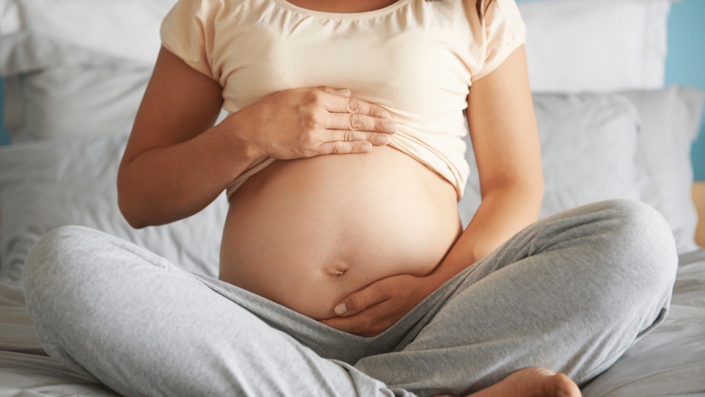 Mulher grávida sentada e segurando a sua barriga como se estivesse acariciando