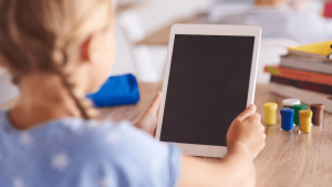 Criança com tablet na mão representando o uso de IA com crianças
