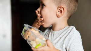 Imagem mostra criança comendo comida saudável com as mãos